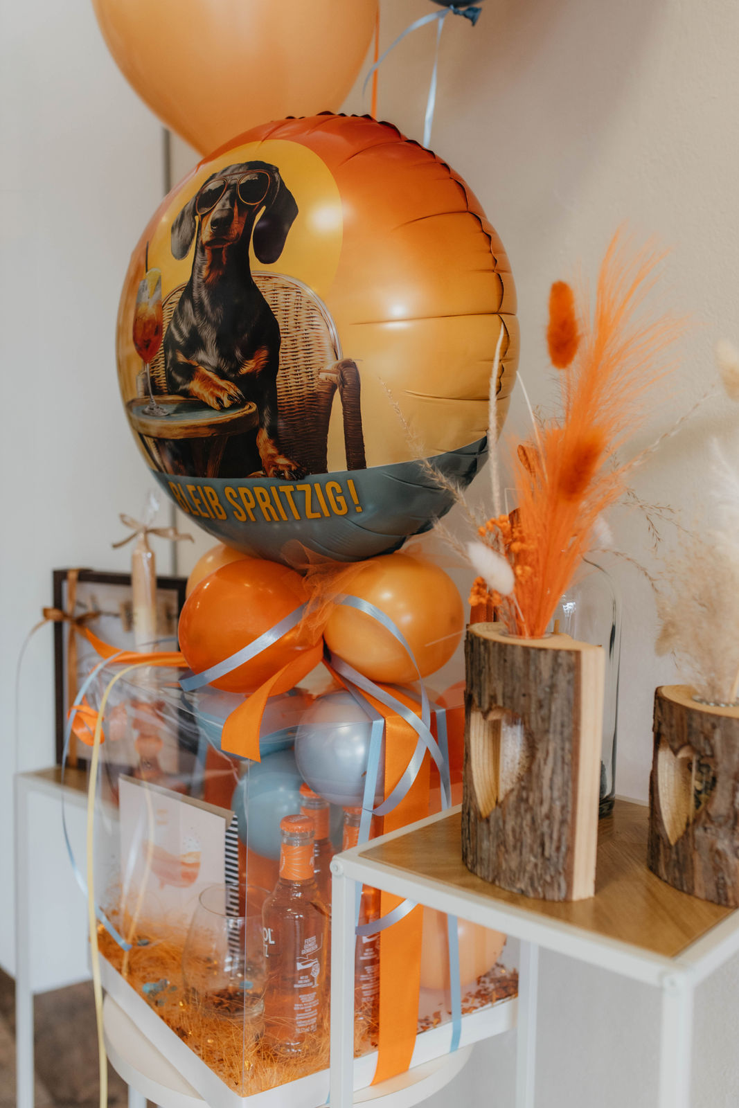 Ein großer orangefarbener Luftballon mit Hundemotiv steht neben bunter Dekoration