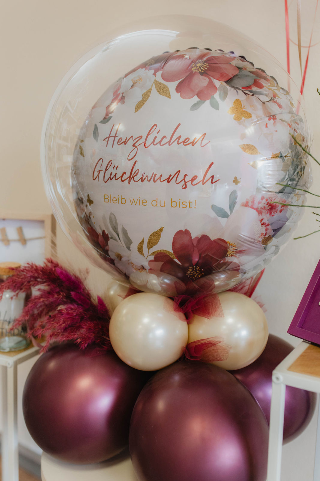 Großer Geburtstagsballon mit floraler Verzierung und Aufschrift in Gold und Rot