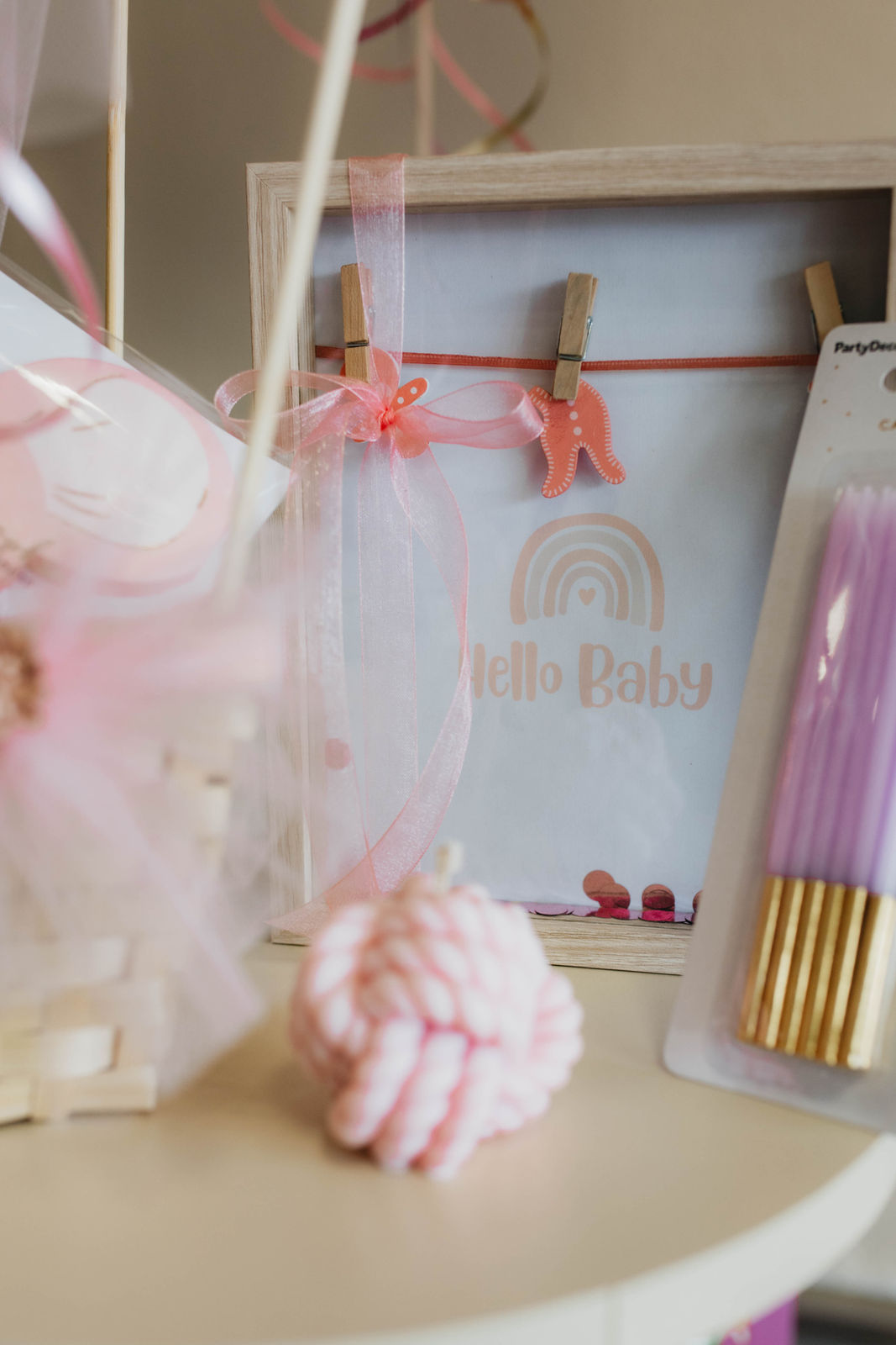Ein helles Baby Willkommensschild mit Regenbogenmotiv und rosa Akzenten ist zu sehen