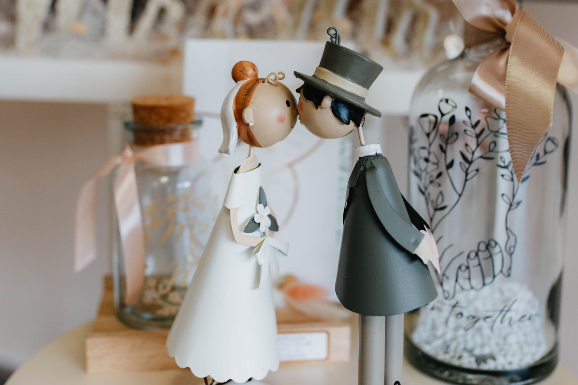Zwei stilisierte Figuren im Hochzeitsoutfit mit freundlichen Gesichtern berühren sich