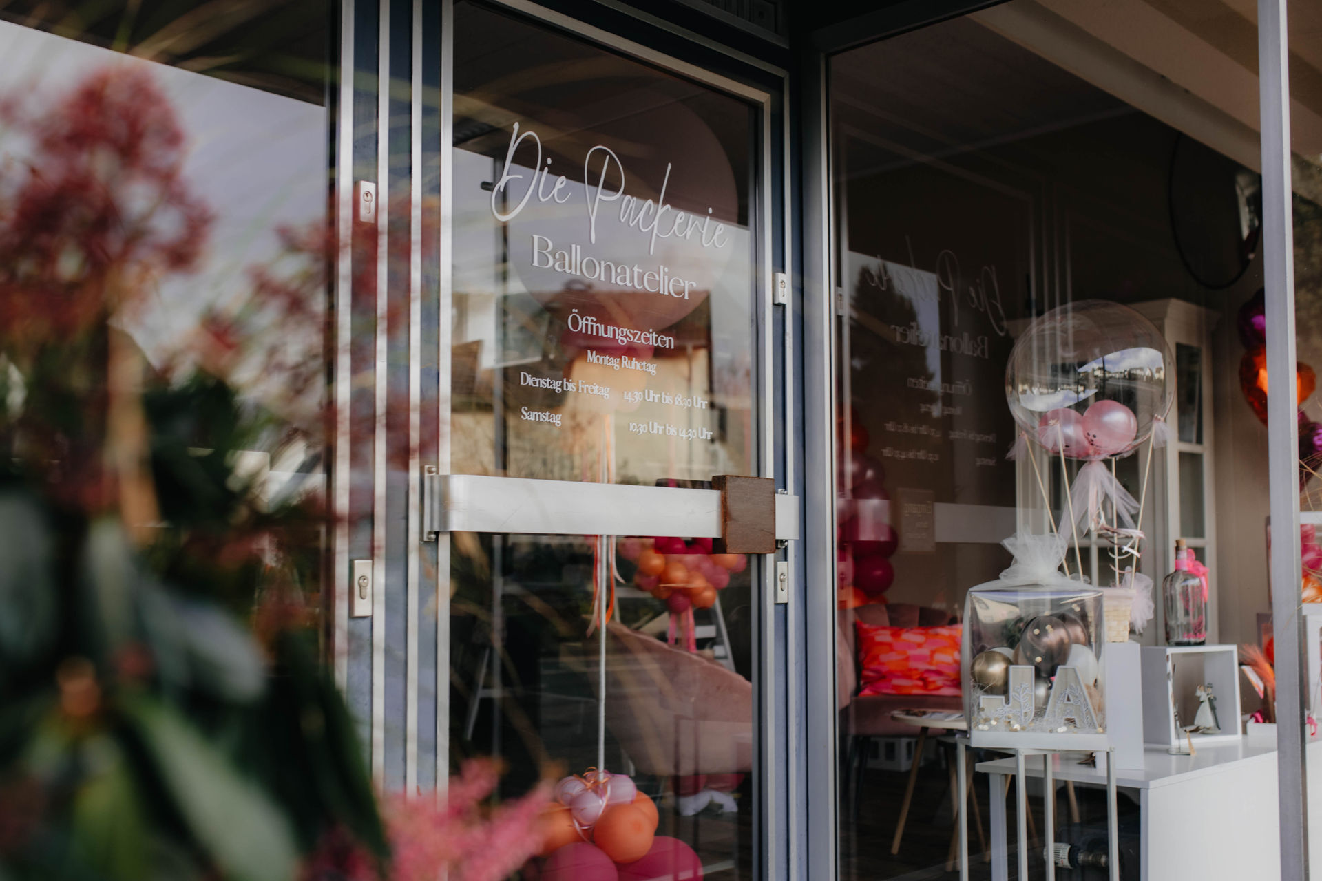 Ein Schaufenster mit rosa und weißen Luftballons und dekorativen Elementen im Inneren