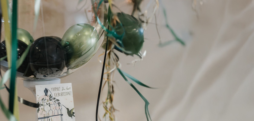 Bunte Luftballons und schimmernde Bänder hängen dekorativ an einem Geschenketisch